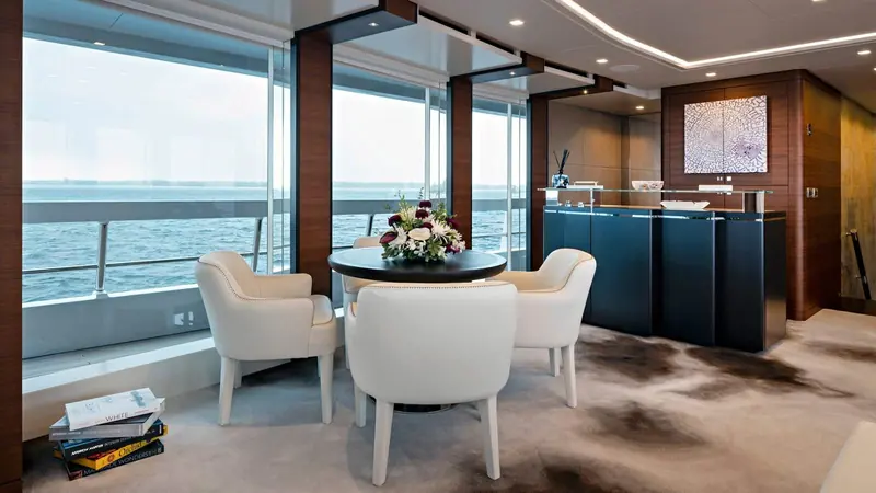 Ela's main-deck dining nook, set apart from the bar behind it so the boat reads as two distinct entertaining spaces rather than one open room.