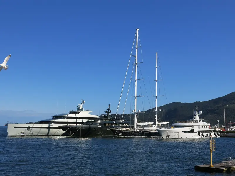 Savannah alongside in La Spezia harbour next to sailing yachts, giving a sense of her full 83.5 metre length and the low, curved bow that runs into the tender garage.