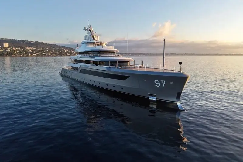 Grey paint and a bow number mark this motor yacht lying at anchor at first light.