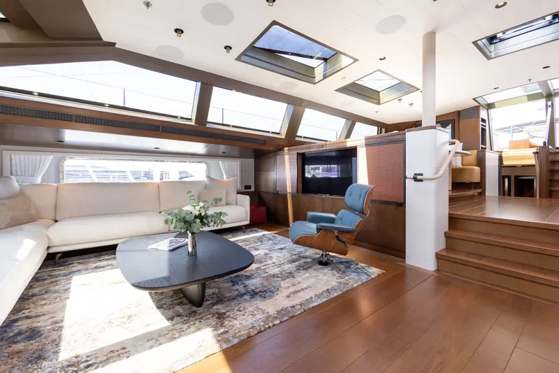 The same hull after her 2023-2024 refit and rename to Ravenger, this saloon restyled by Design Unlimited to a Scandinavian brief of pale oak and white upholstery for a new owner, a look that helped win the yacht a 2025 World Superyacht Award for best refit.