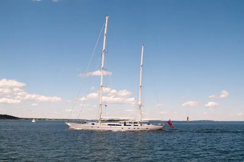 Timoneer under power in Casco Bay, Maine, in July 2012, her name lettered on the hull below the aft mast. Built by Vitters in 2001 to a 44.75m Dubois design, she remains an active cruising yacht more than two decades after delivery.