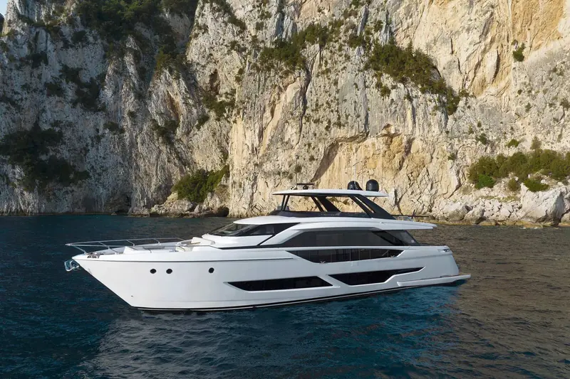 The Ferretti Yachts 860 at anchor beneath a limestone cliff on the Amalfi coast, Filippo Salvetti's exterior profile set against the rock.