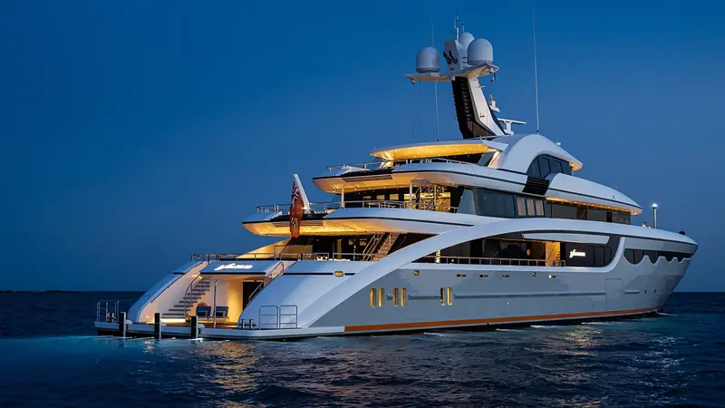 Soaring/Starlust's stern and swim platform lit at night. The sweeping waterline stripe and scalloped hull windows were drawn, in the studio's own words, so the yacht would not be mistaken for any other on the horizon.