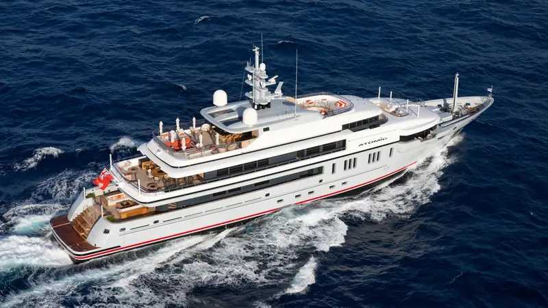 The 64 metre sailing yacht Atomic underway, her dark hull cutting a wake under full sail.
