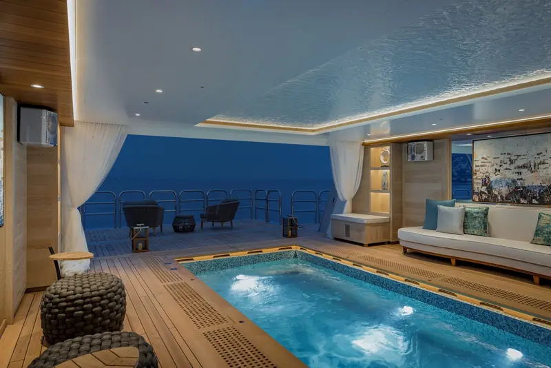 The indoor-outdoor spa pool on Victorious opens straight onto a rail-only deck, no bulwark breaking the view out to sea.