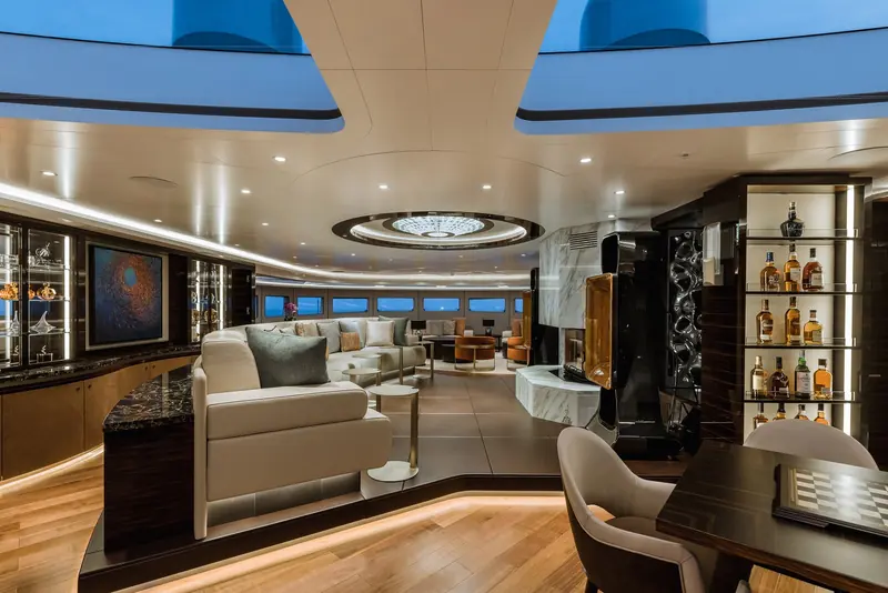 Victorious's main salon, with a backlit onyx fireplace and a full-height whisky cabinet built into the ebony joinery.