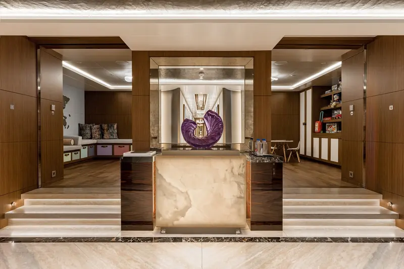 The lower lobby on Victorious, an onyx reception desk under a mirrored surround with a hand-blown glass sculpture at its centre.