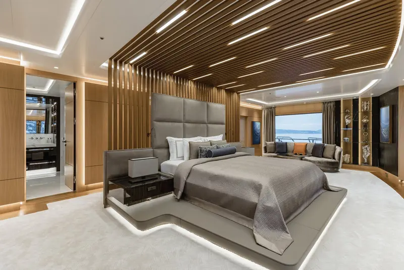 The owner's suite on Victorious, its slatted timber canopy built low over a plinth bed with a private aft terrace beyond.