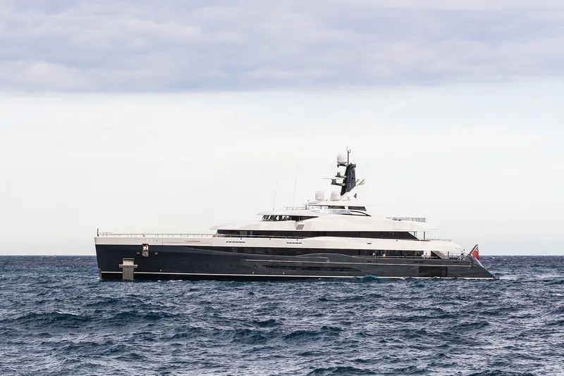 The dark-hulled 74.5-metre superyacht Elandess makes way off Monaco under an overcast sky.