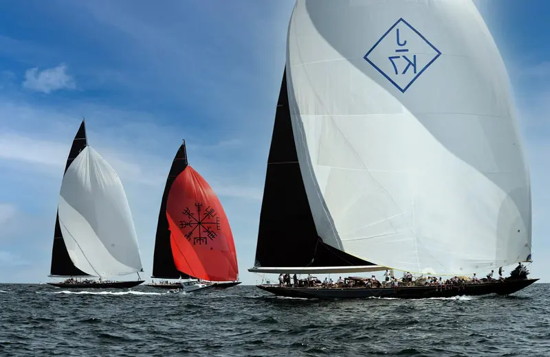 Svea (right, black hull, sail mark K/J), the Hoek Design J-Class completed by Vitters in 2017, running downwind at the 2017 J Class World Championship in Newport alongside Topaz (centre, red spinnaker) and the 1933 original Velsheda (left), which is not a Hoek design.