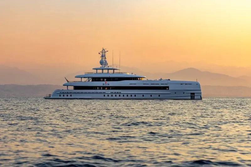 Bijin lies still on a glassy sea as the sun drops behind coastal hills.