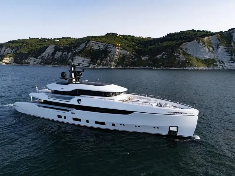 Chalk cliffs rise behind Night Fury II as she idles close inshore.