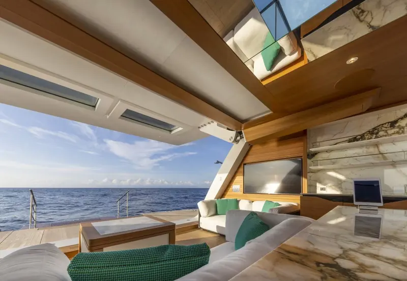 Aboard M/Y C, the aft lounge opens fully to the sea beneath a glass roof, marble and teak meeting at the bar.