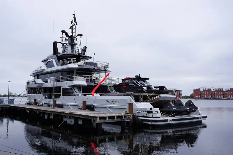 Two tenders and a stack of jet skis ride the aft deck, which the brief turned into a working platform rather than a sundeck.