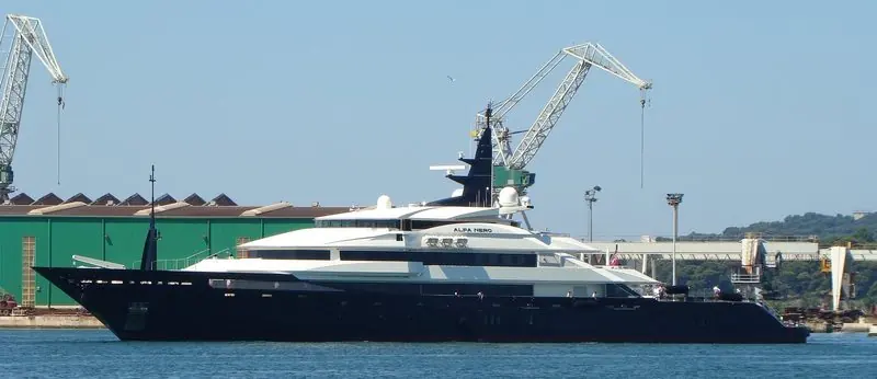 Shipyard cranes stand over Alfa Nero as she lies at the quay in full profile.