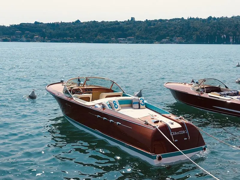 Two varnished Riva runabouts ride to a mooring on Lake Garda.