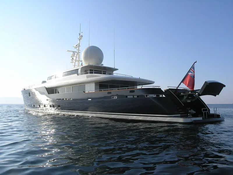 Galileo G seen from astern in the same Sardinian anchorage, with the transom garage open onto the bathing platform.