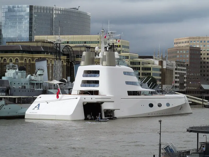 Motor Yacht A moored on the Thames in London in September 2016, beside the museum ship HMS Belfast. Her bow carries the single-letter name and Hamilton, Bermuda, her port of registry at the time.