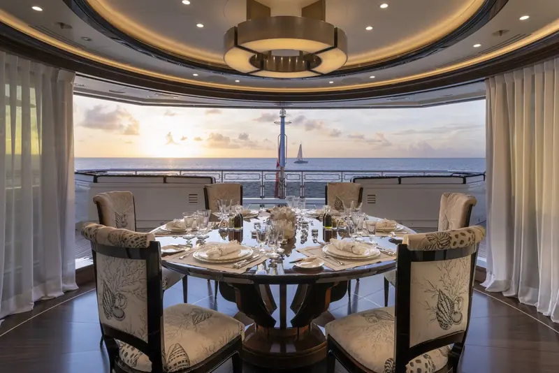 The main dining room aboard Alfa Nero, its curved glazing and coral-print chairs part of Pinto's scheme for the yacht's principal entertaining spaces.