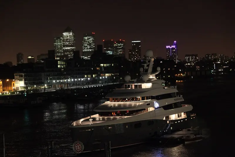The 87-metre Aviva lies on the Thames off Canary Wharf at night, her interior lit through Reymond Langton's window line - one of the few night frames the yard's owner-commissioned photography ever released.
