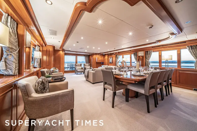 The dining room aboard Marama, table set for guests with the water visible through the windows.