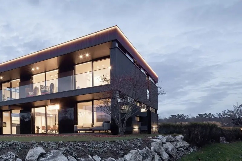 Warm light fills the glazed studio building at dusk.