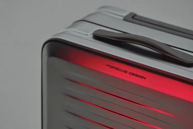 Red light washes the ribbed flank of the case beside its leather grab handle.