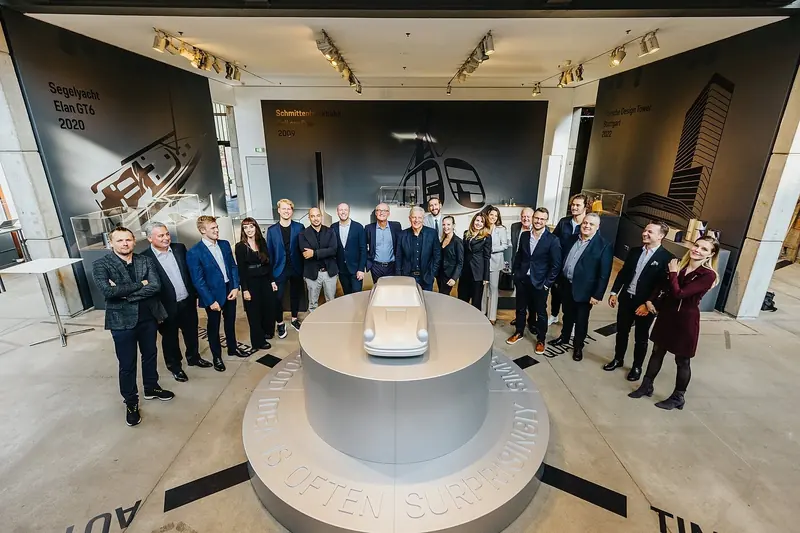 The Studio F. A. Porsche team at their Zell am See exhibition, 'Form Equals Function', with the sailing yacht Elan GT6 credited on the wall behind them among the studio's other transport work.