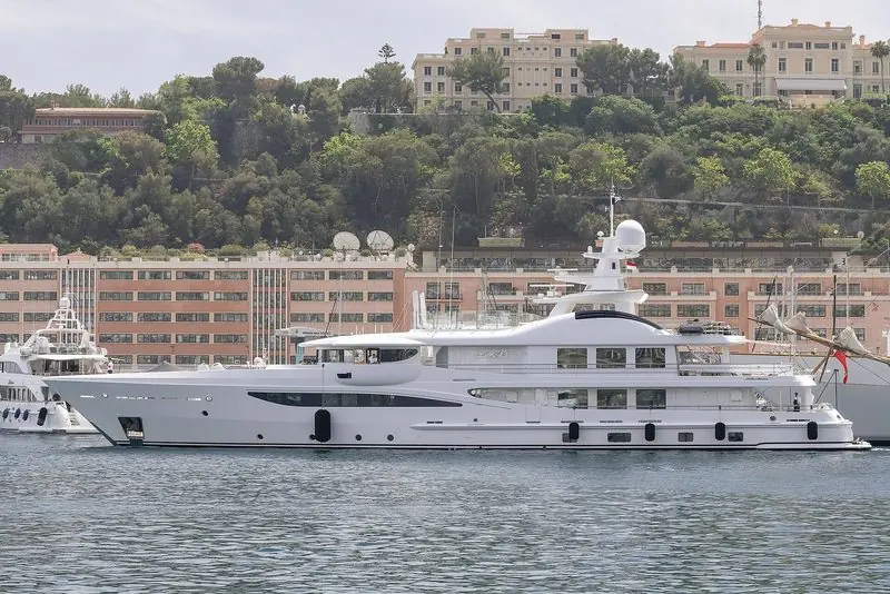 White from stem to stern, La Mirage lies alongside beneath a wooded hillside.