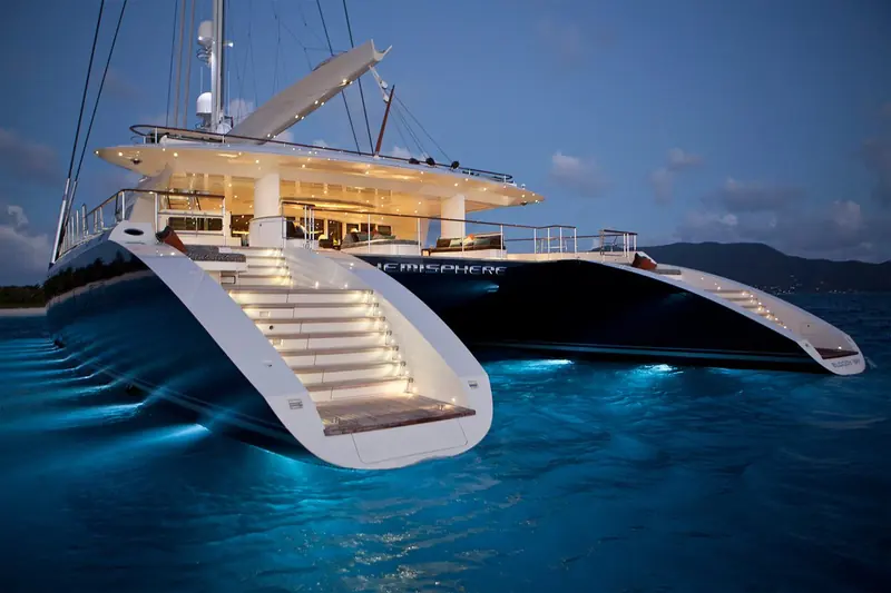 Hemisphere at anchor at dusk, her transom stair lowered and tender Bloody Bay on davits; she was the largest sailing catamaran in the world when Pendennis launched her in 2011.