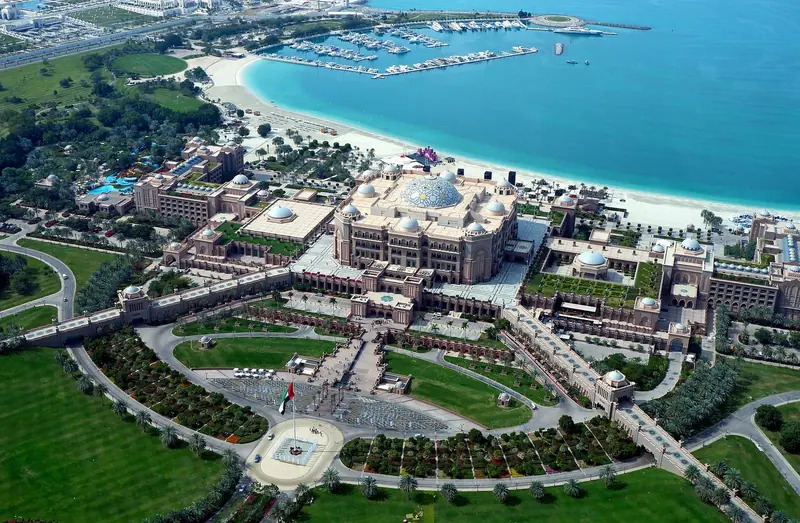 Emirates Palace and its own marina on the Abu Dhabi corniche, seen from above. The two ranks of berths at the top of the frame sit a few hundred metres from the hotel's front steps.