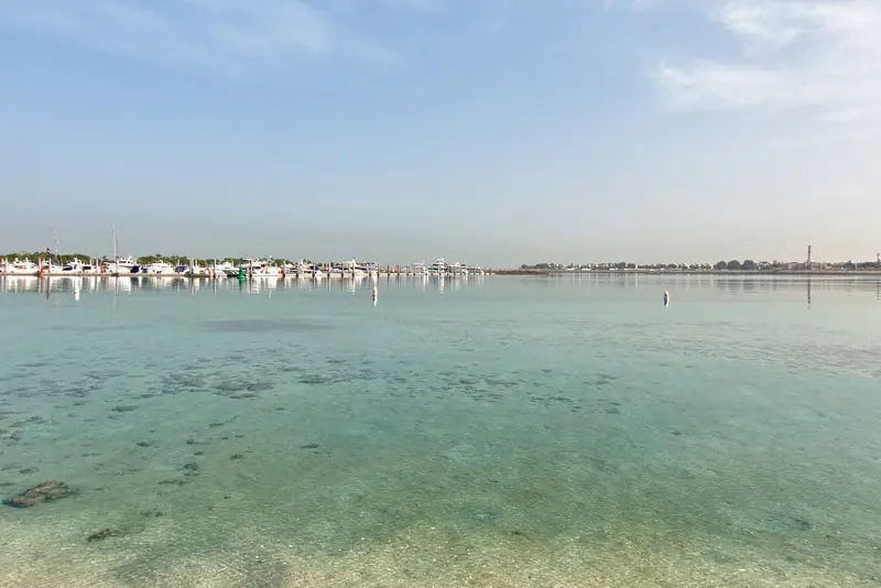 The Emirates Palace hotel harbour at low tide, the shallow turquoise water that the marina's approach channel had to be dredged through to reach seven metres.