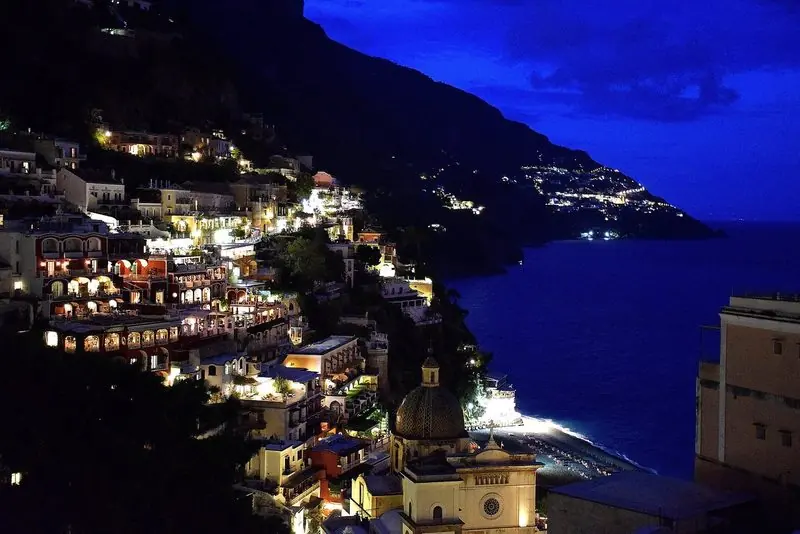 Positano lit at night, the view guests get from an anchored boat.