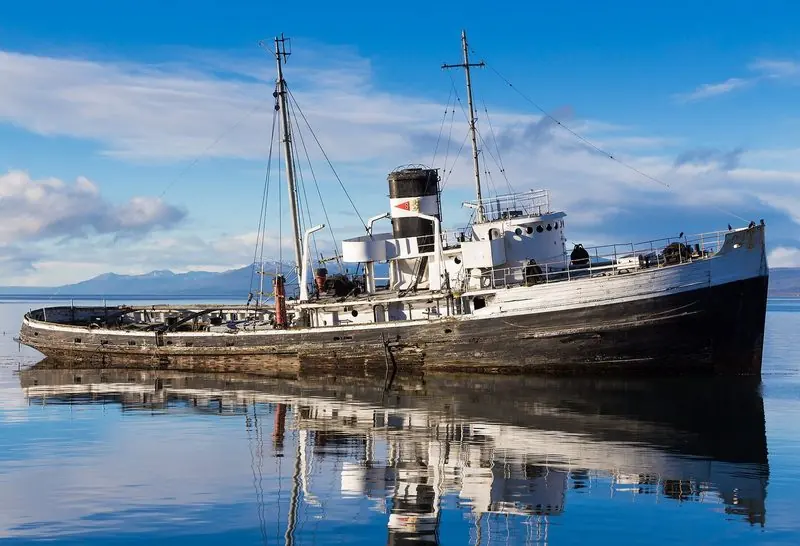 Further north, a derelict steam tug sits aground off the town waterfront, still upright and reflected in a dead calm channel.