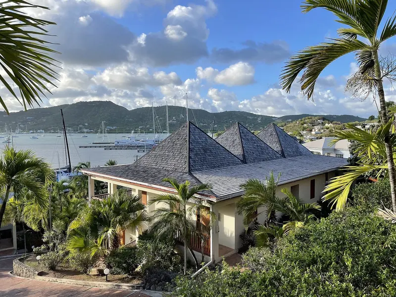 The old Antigua Yacht Club Marina buildings look out over Falmouth Harbour and its anchored fleet, rebuilt after the October 2023 fire as the Antigua Superyacht Marina and Resort.