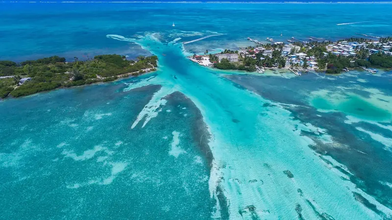 A deep-water channel cuts through the flats into Caye Caulker, the shading in the shallows marking sand, turtle grass and coral as clearly as a chart.