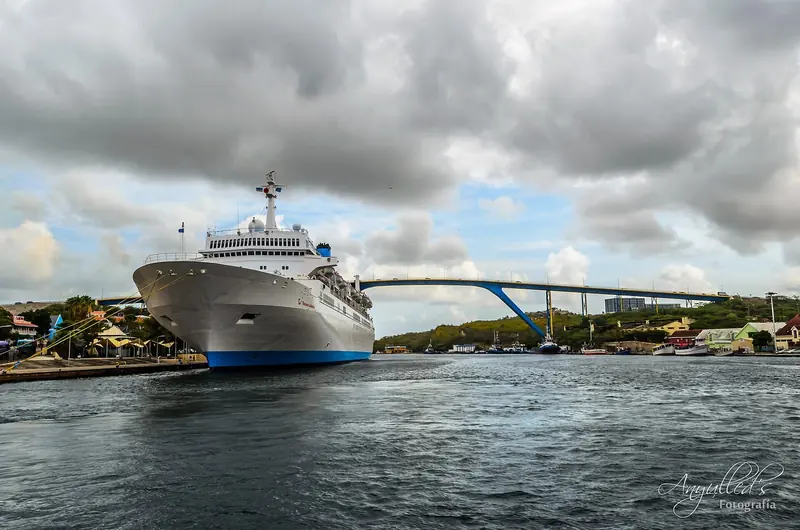 A cruise ship passes beneath Willemstad's Queen Emma pontoon bridge at the mouth of St Anna Bay, Curacao.