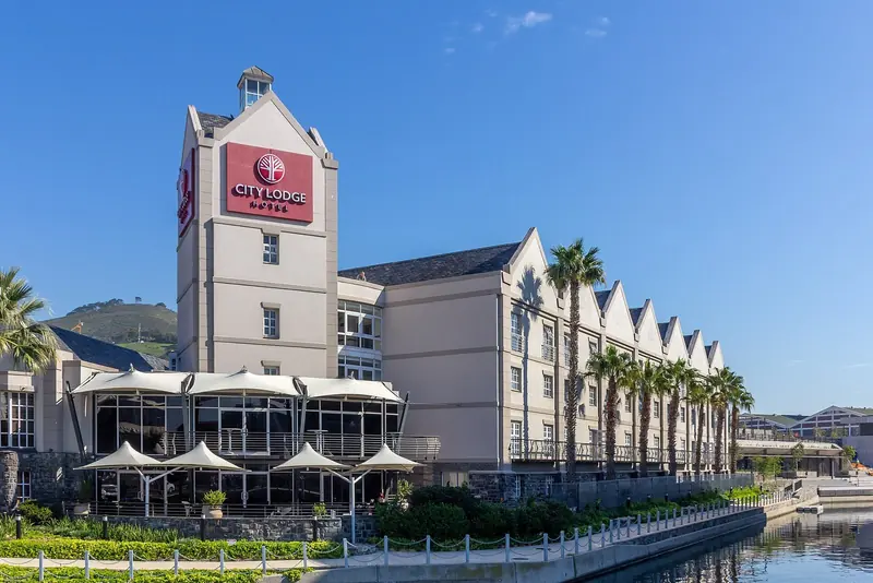 A canal-side hotel lines the water at the Waterfront, palm trees and canopied restaurant terraces running the length of it.