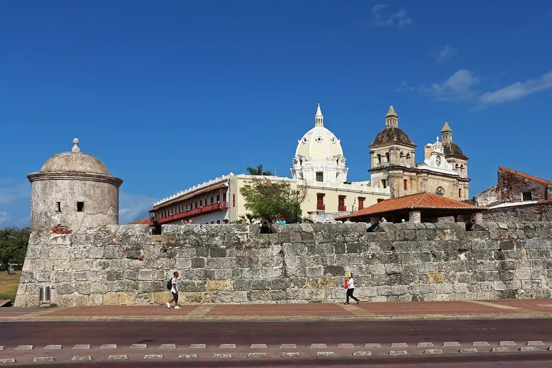 The Baluarte de San Ignacio bastion on Cartagena's colonial walls, with the twin towers of the cathedral behind it. The full fortification ring is still intact after nearly four centuries.