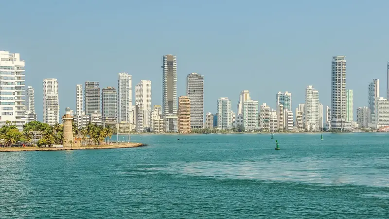 The Castillogrande lighthouse marks the channel into Cartagena bay, with the modern towers of Bocagrande, the city's marina and hotel district, behind it.