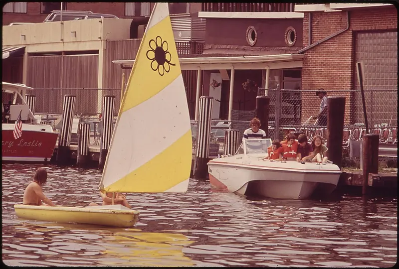 Sailing dinghies at a dock on the Bay, evoking the informal picnic-supper racing Annapolis Yacht Club started in 1959.