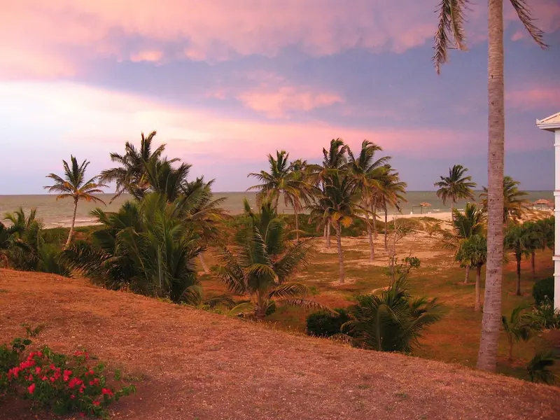 A storm-lit sunset closes over the beach on the Varadero peninsula, palms bent in the onshore wind that builds most afternoons.