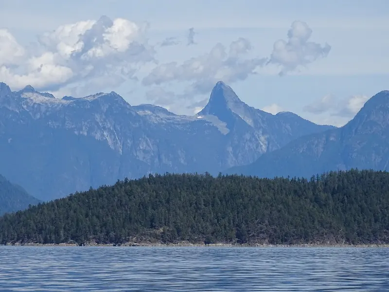 Mount Denman rises behind Desolation Sound, seen across the anchorage from a cruising yacht at water level.