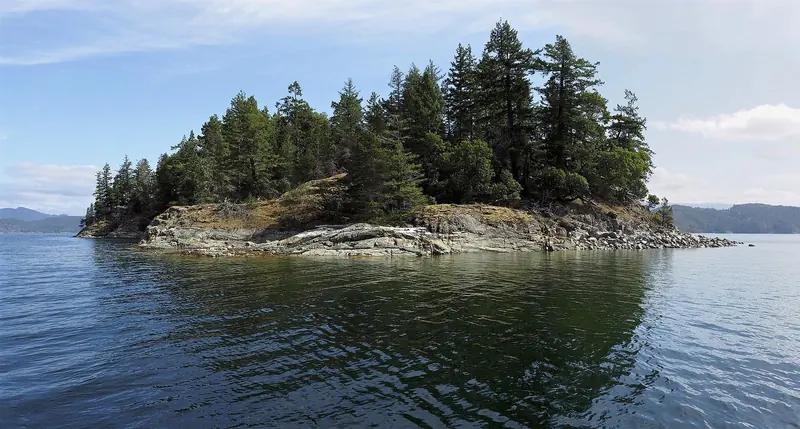 A small forested islet in the Gulf Islands, its granite shoreline typical of the skerries scattered through this cruising ground.