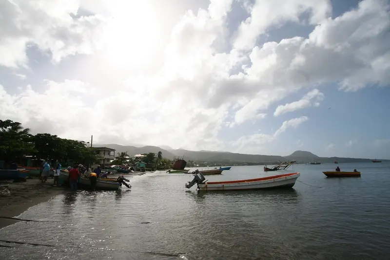 Small wooden boats sit at the water's edge in Portsmouth, the fishing and yacht-services town on Prince Rupert Bay.