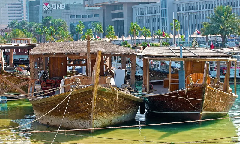 Traditional dhows moored under a Gulf skyline, the working craft the region used before any of the marinas existed.