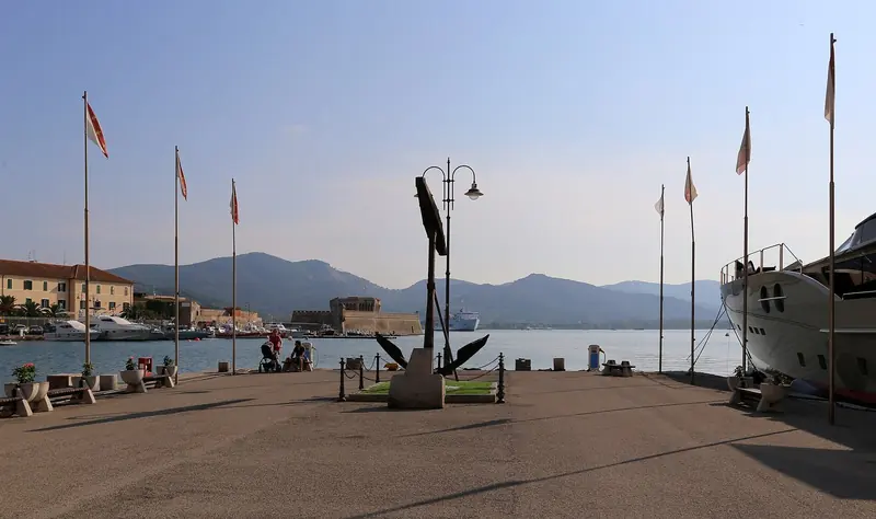 The anchor monument on Portoferraio's quay, flags out along the promenade where the town's cafes and the passenger ferries from Piombino both work.