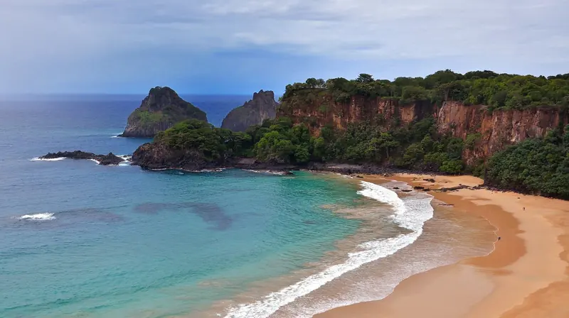 Praia do Sancho, framed by the Morro Dois Irmaos rock towers, one of the beaches reachable only by boat or on foot through the national park.