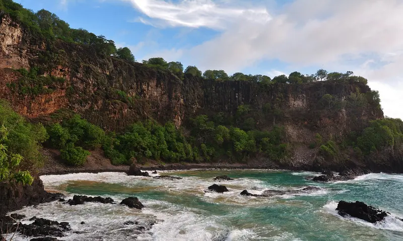 Praia do Sancho seen from the water, the vantage a yacht anchored offshore actually gets of the island's cliffs and coves.