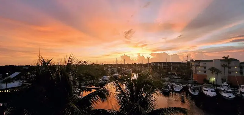 Sunset over a Key Largo basin puts sportfishers into silhouette along the docks, the water still between the palms.